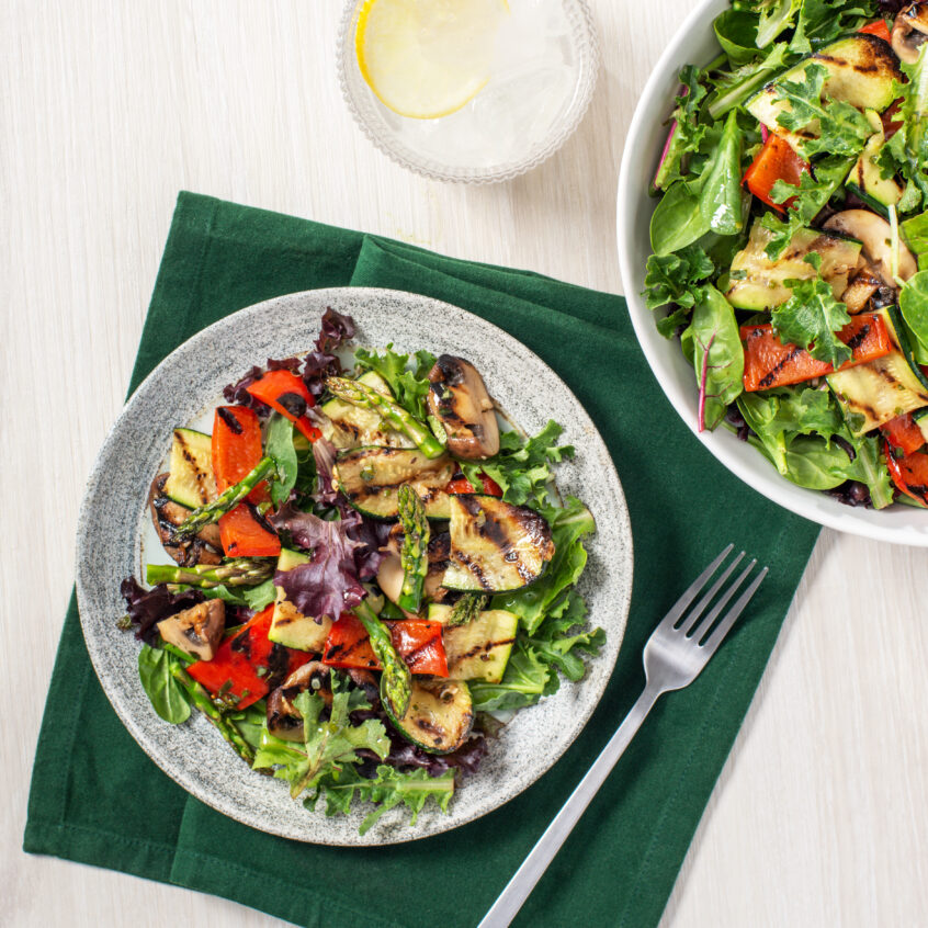 Chopped & Grilled Vegetable Salad on a plate placed on top of green table clothes.